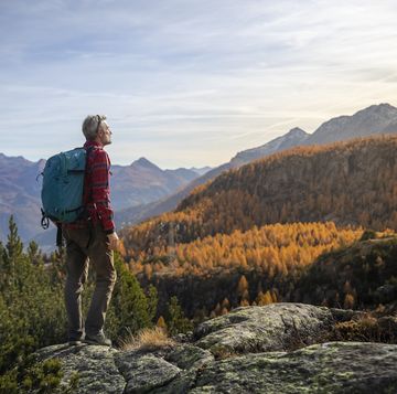 hiker standing in front of the mountain valley in autumn