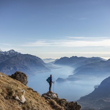 hiker standing on mountain, looking at lake como, italy
