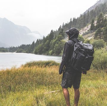 hiker with a backpack watching the lake sourrounded by mountains