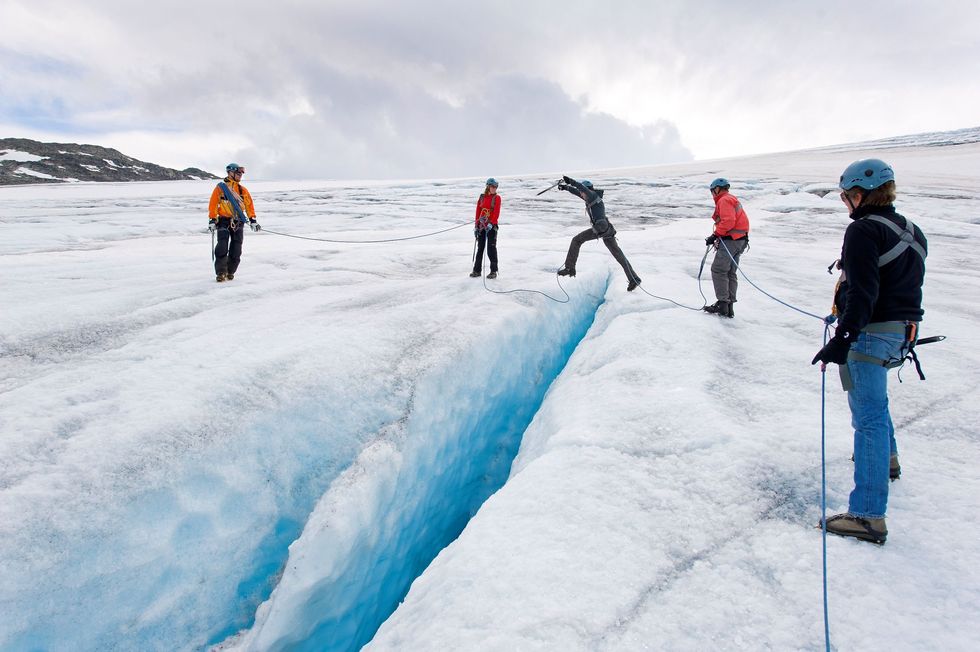 Wandelaars springen over een spleet in de Hardangerjkulen gletsjer in Noorwegen Star War fans herkennen deze omgeving mogelijk als de afgelegen ijsplaneet Hoth waar Han Solo Luke Skywalker redt nadat zijn tauntaun door een wampa werd aangevallen