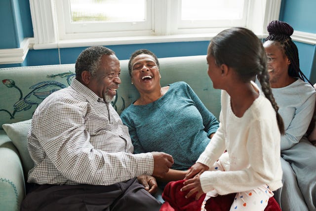 high angle view of cheerful grandparents talking with granddaughters while sitting on sofa at home