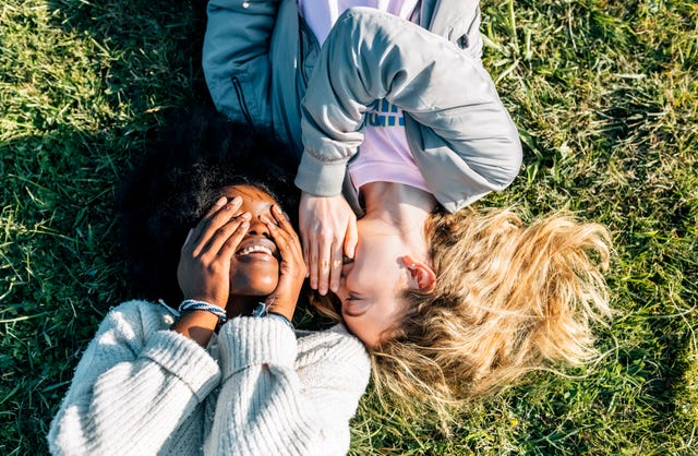 two best friends telling secrets lying in the grass