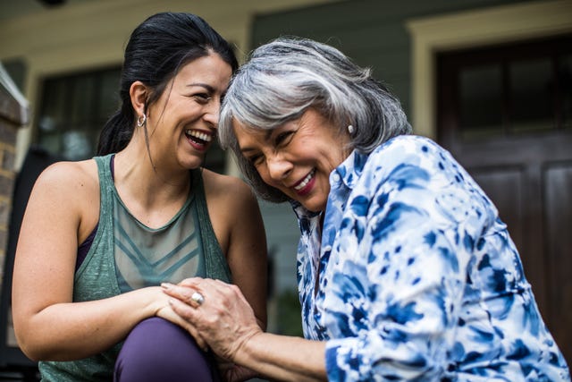 senior woman and adult daughter laughing on porch