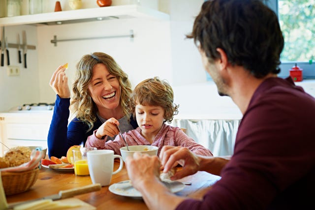 happy family of three enjoying breakfast at table in domestic kitchen