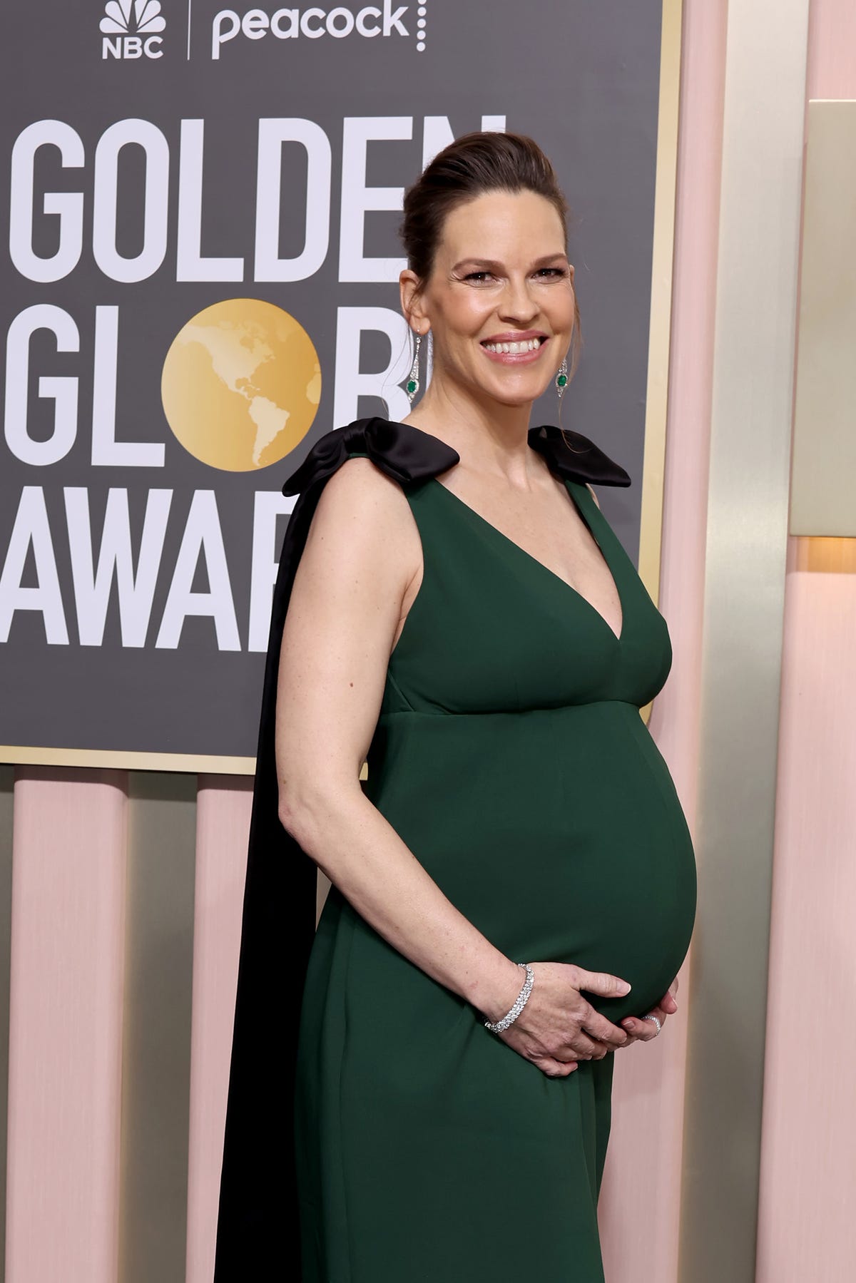 Hilary Swank and her bump glow in green on the red carpet