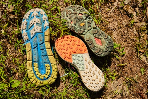 several shoe soles are displayed on the ground, showcasing different tread patterns and colors
