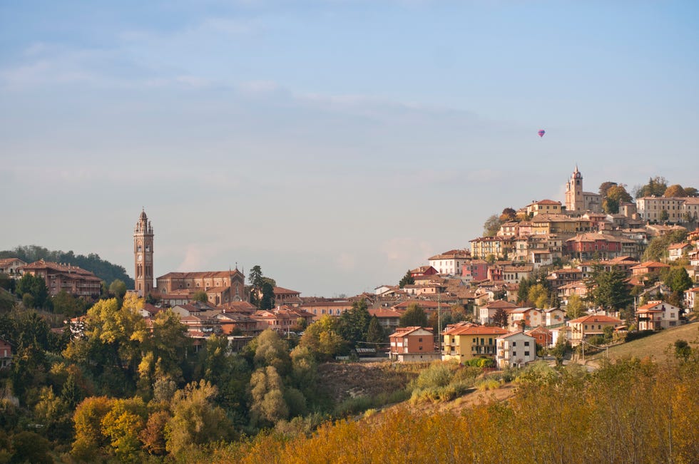 hillside village with hot air balloon in background, monforte d'alba, italy