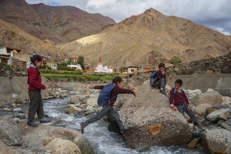 IndiaSchoolkinderen in het dorpje Gya in de regio Ladakh steken een rivier van smeltwater over die in de Indus uitmondt Op zijn westwaartse route van Tibet naar Pakistan loopt de Indus door Ladakh een woestijnachtig hooggebergteplateau in het uiterste noorden van India In de afgelopen decennia smelten de gletsjers die de Indus van water voorzien steeds sneller als gevolg van de klimaatverandering wat tot ongekende overstromingen heeft geleid In 2014 werden twee huizen in Gya door een stortvloed uit een smeltwatermeer verwoest
