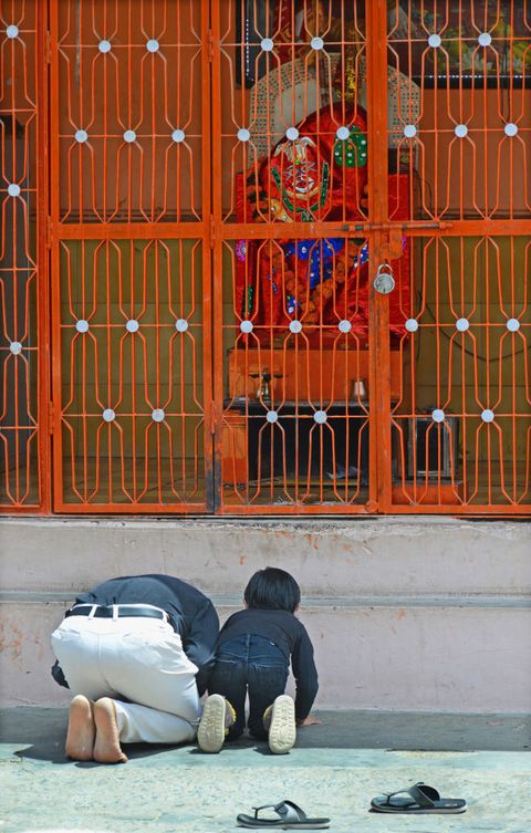 Hindu devotees offer prayers outside a locked temple of...