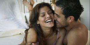 hispanic couple laughing on bed
