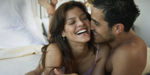 Hispanic couple laughing on bed