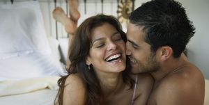 Hispanic couple laughing on bed