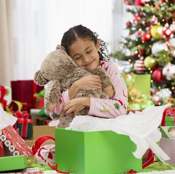 hispanic girl hugging teddy bear christmas gift