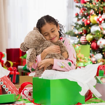 hispanic girl hugging teddy bear christmas gift