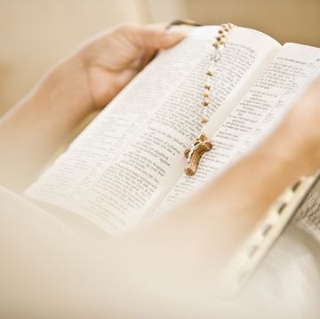 woman reading the bible with a rosary