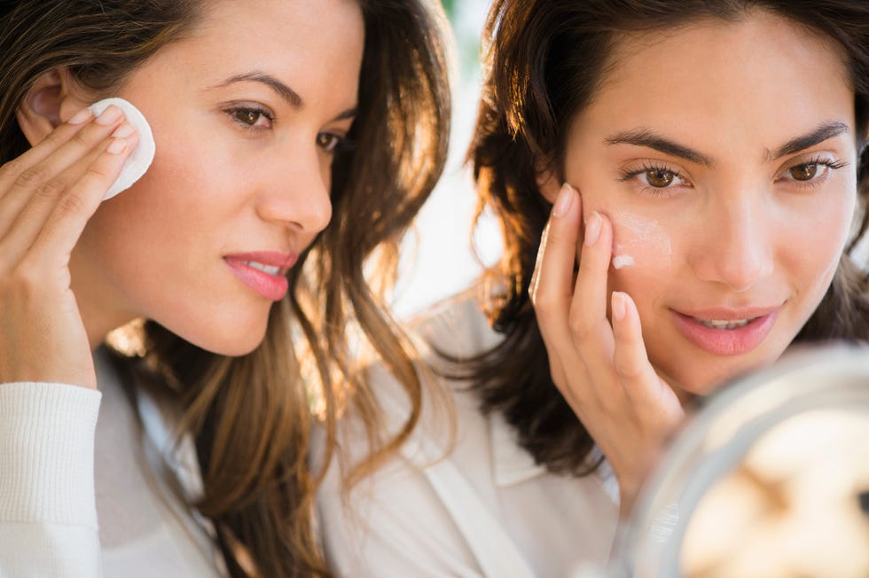 hispanic women applying makeup in mirror