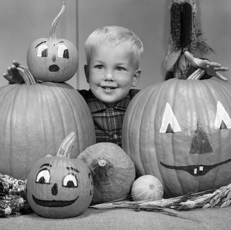1960s smiling blond boy surrounded by pumpkin patch jack o' lantern