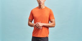 man wearing an orange athletic shirt with hands clasped