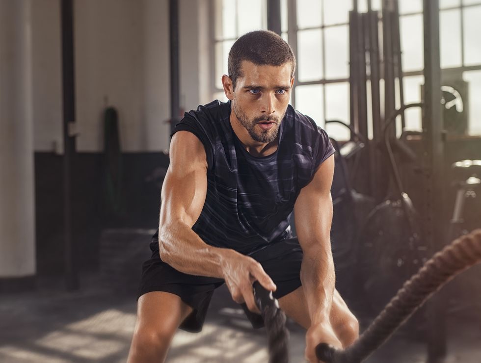 athletic young man doing some fitness exercises with a rope determined fit guy doing battle ropes exercise at the grunge gym handsome man training with effort shutterstock id 1442721002 purchaseorder job client other