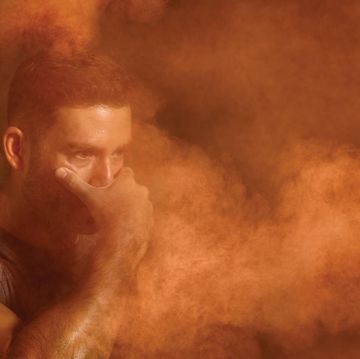 man covering his face amidst orange air particles