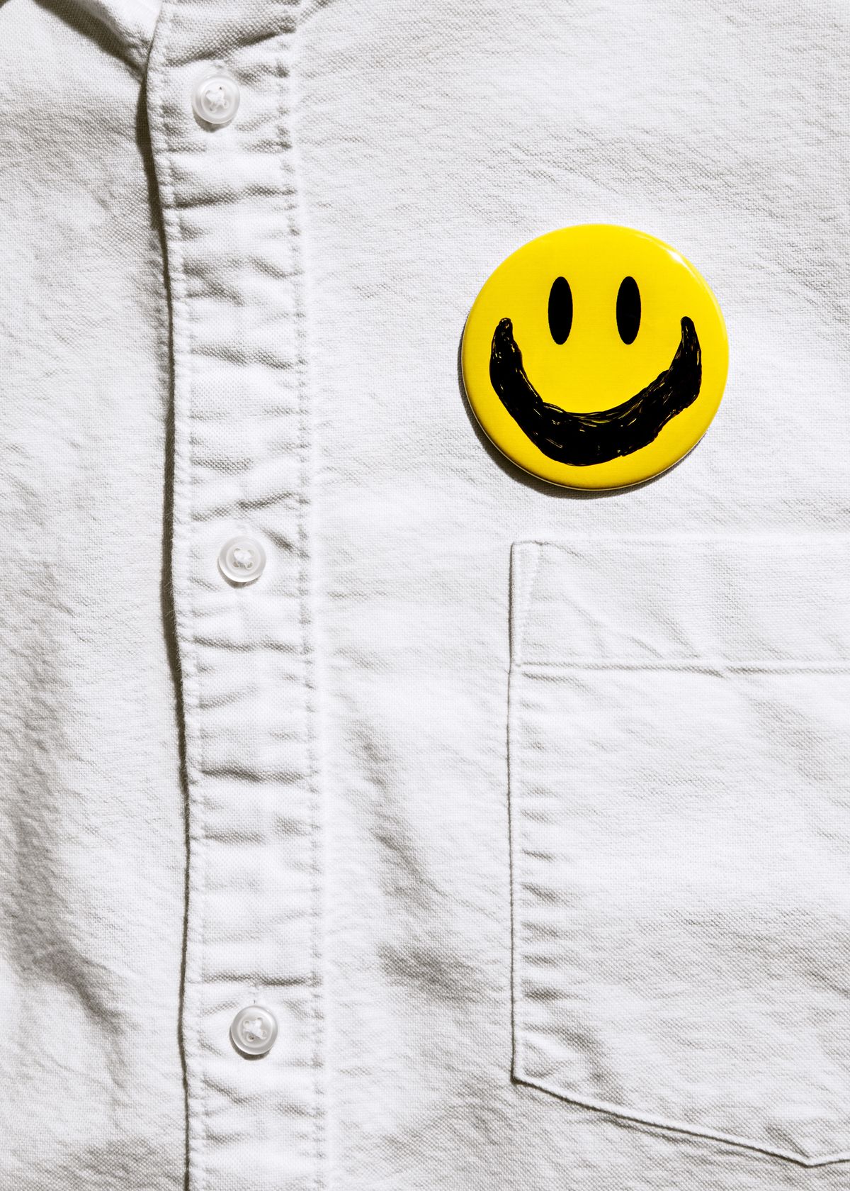 man's shirt with smiley face button on it