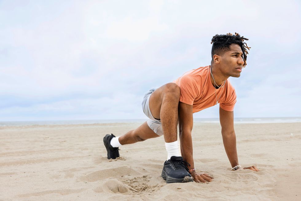 a man squatting on sand