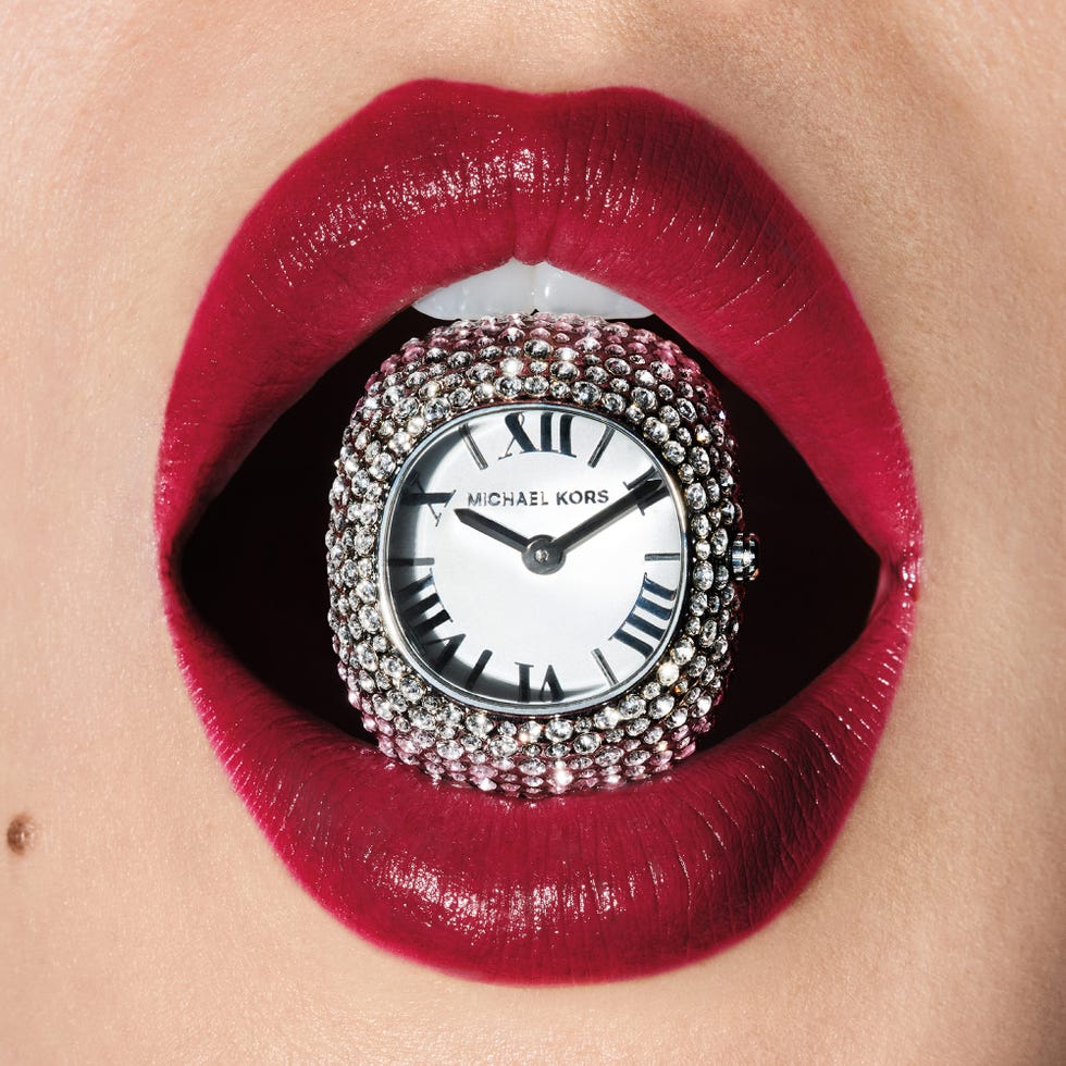 a decorative watch held in a mouth with bold red lipstick