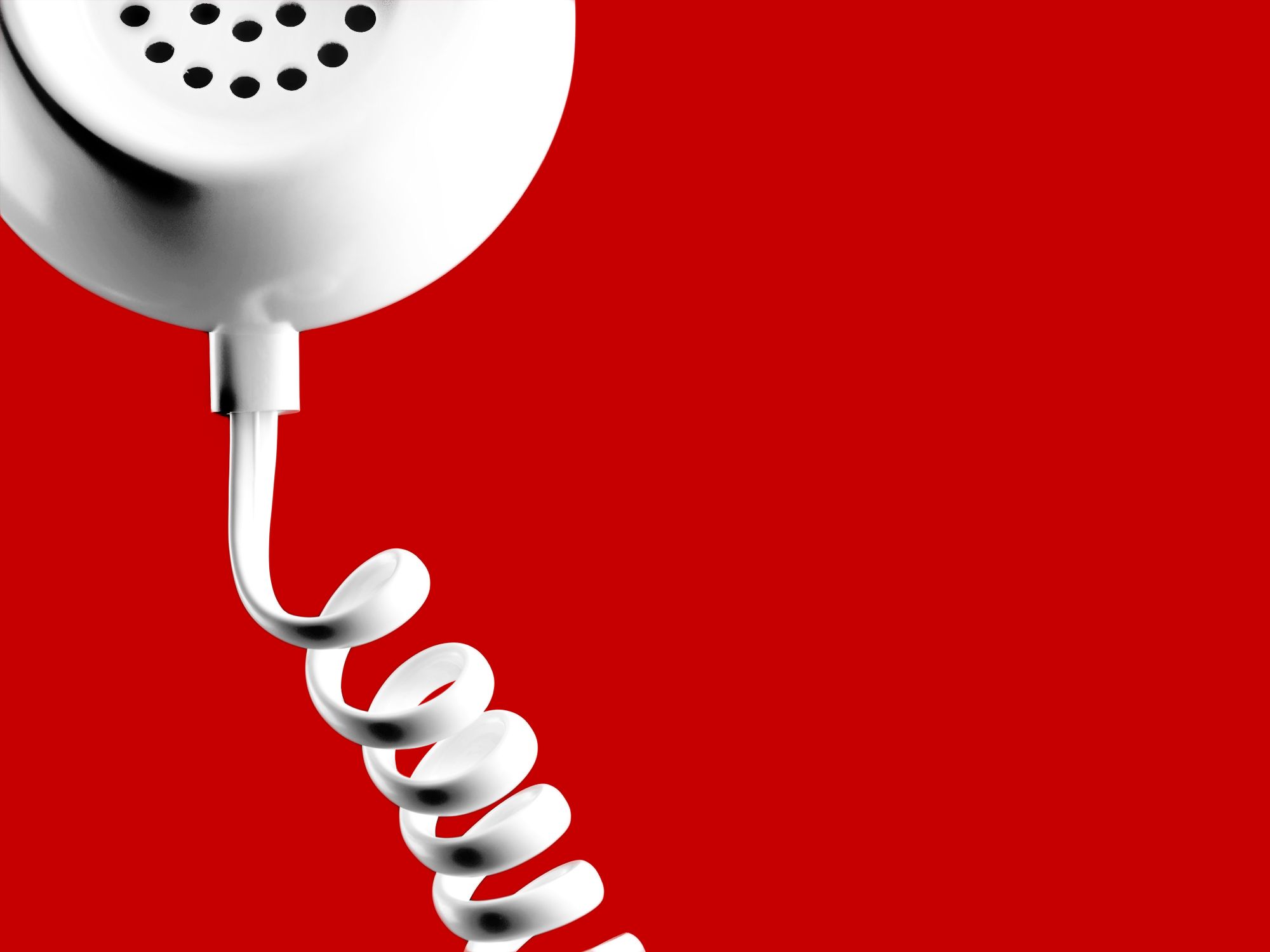 closeup of phone with coil phone chord on red background