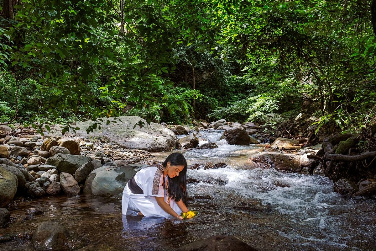 Ati Quigua voert een beschermingsritueel uit voor een rivier in de Sierra Nevada de Santa Marta een kustgebergte in het noorden van Colombia Quigua is politica en milieuactivist Ze behoort tot de inheemse Arhuaco en verzet zich tegen de mijnbouw en grootschalige projectontwikkeling die de natuur in het biosfeerreservaat bedreigen