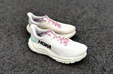 a pair of pale pink hoka running shoes on a pavement