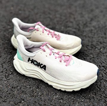 a pair of pale pink hoka running shoes on a pavement a pair of pale pink hoka running shoes on a pavement
