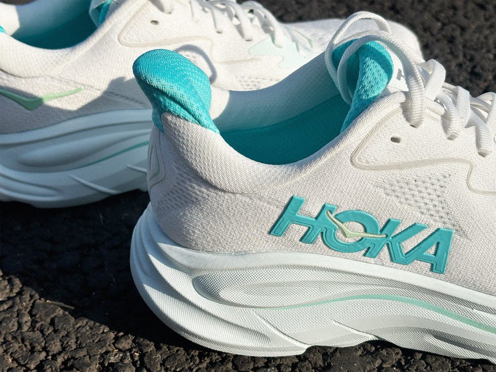 close up of a pair of white hoka running shoes with blue details