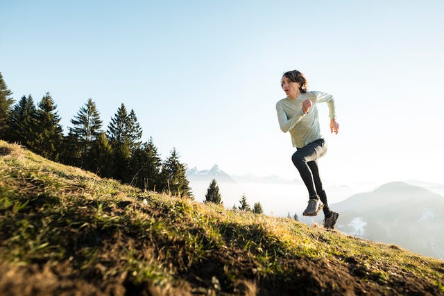 person running on a hill with a mountainous background