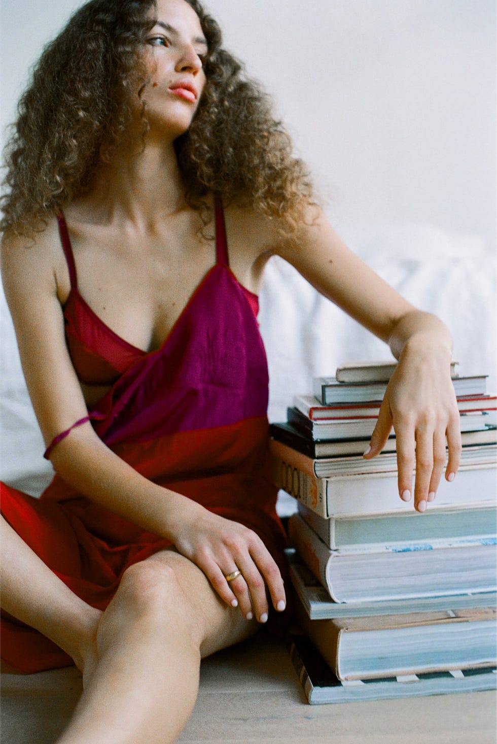 a person in a colorful dress sitting beside a stack of books