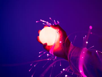 holding a glowing ball, arms wrapped with fiber optics