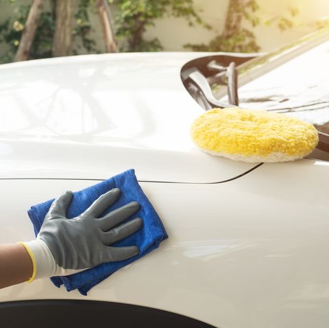 holds the microfiber in hand and polishes the car