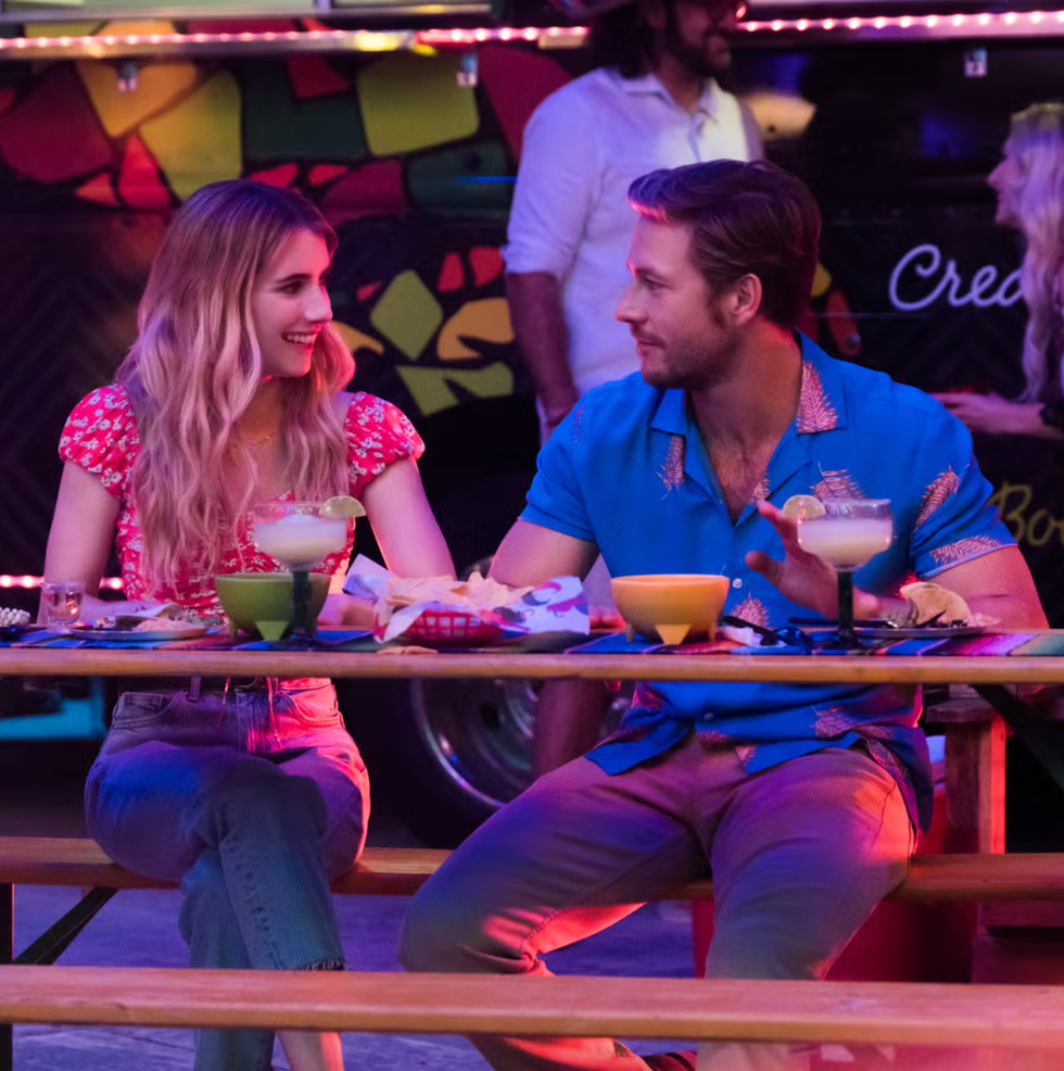 outdoor dining scene with two people at a table featuring food and drinks