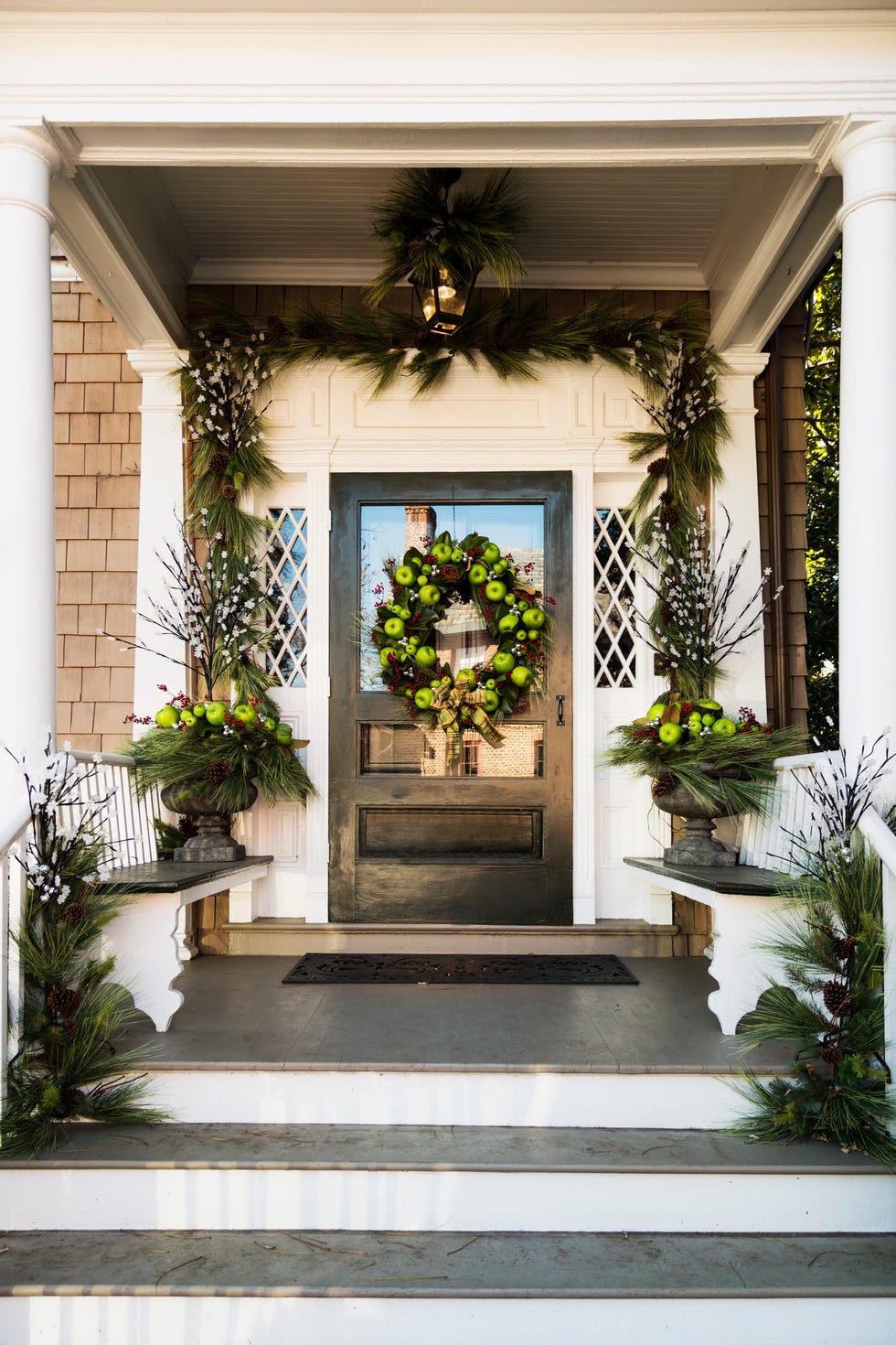 a beautifully decorated front door and porch ready for the holidays