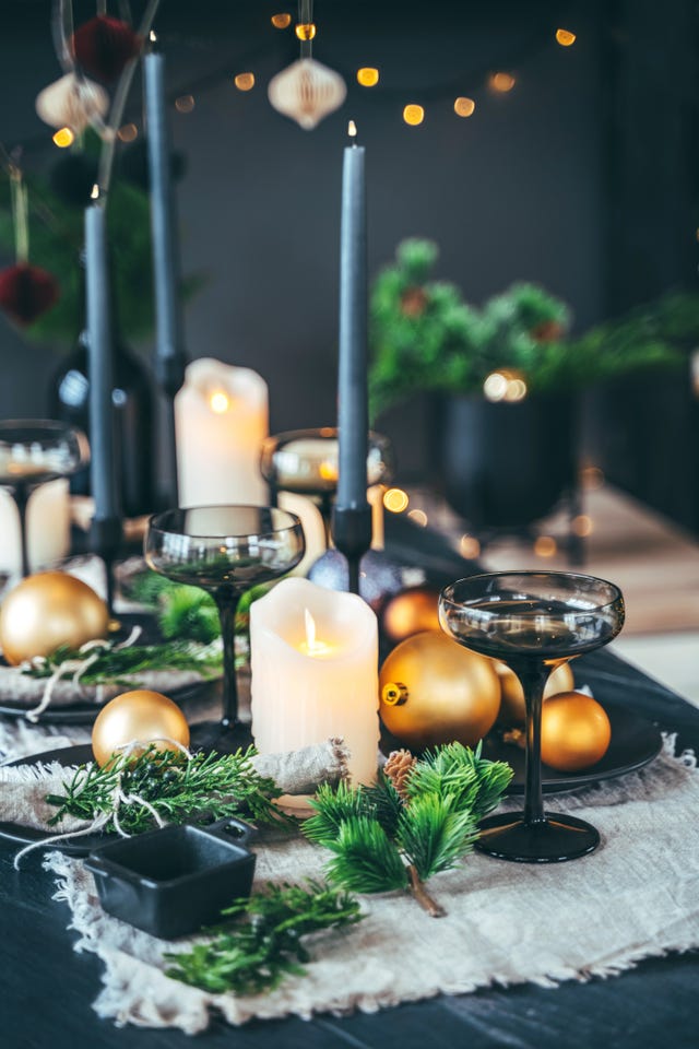 holiday table set up with candle lights, fir tree branches and christmas balls