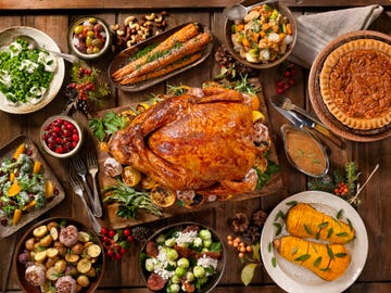 thanksgiving turkey on a table along with side dishes like pecan pie and roasted carrots