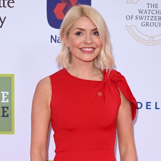holly willough smiling in a red dress at an event she looks happy and calm