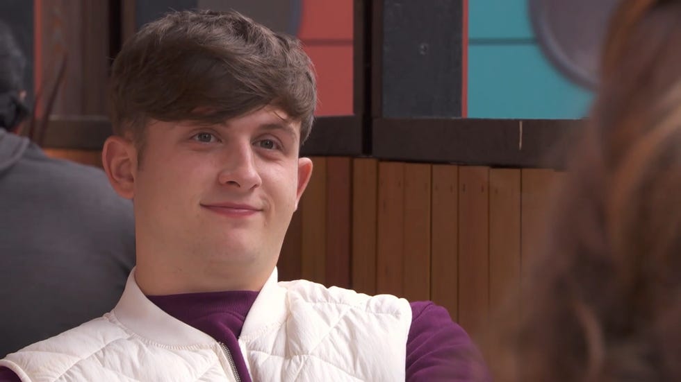 hollyoaks charlie dean wearing a white vest gilet over a purple jumper