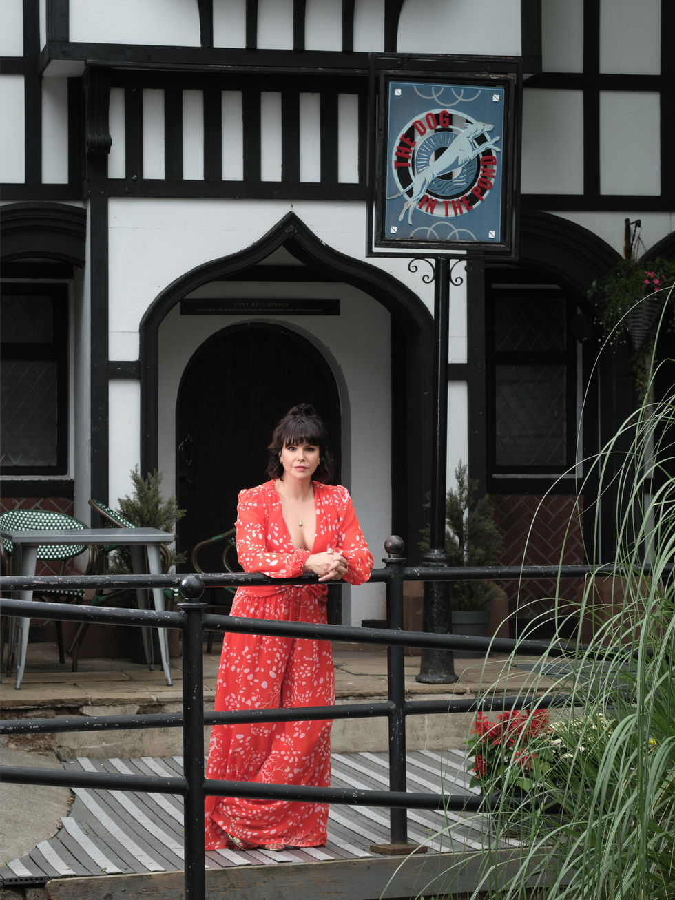 hollyoaks star jessica fox in a red floral dress as she stands outside the dog in the pond