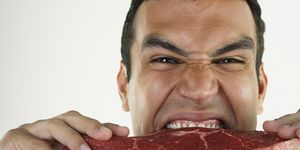 un hombre comiendo carne roja sin cocinar
