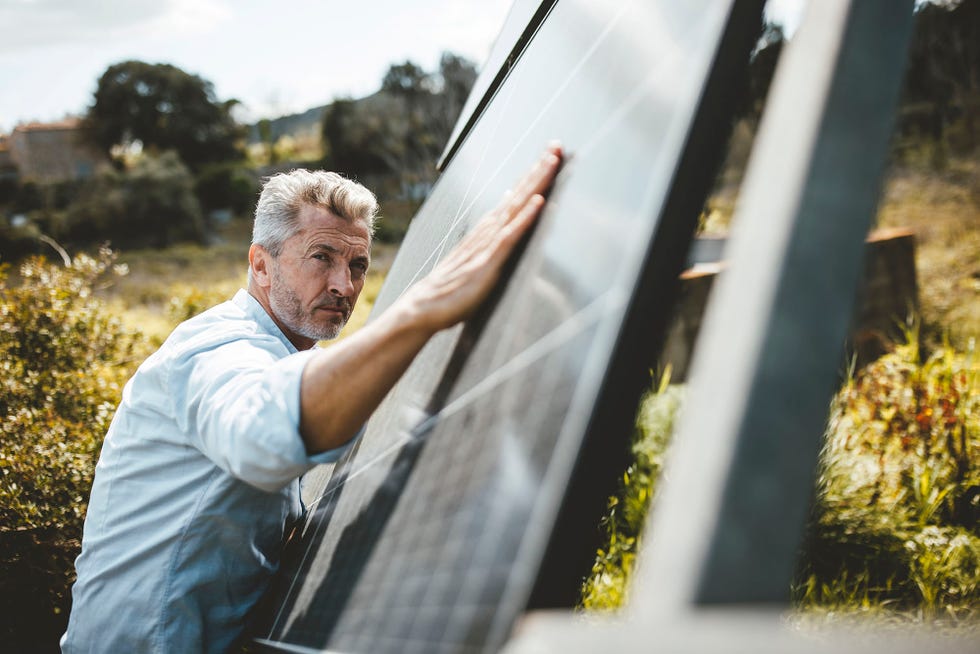 hombre con paneles solares en el jardin