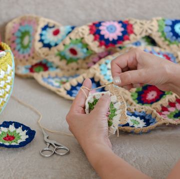 woman crocheting a granny square blanket
