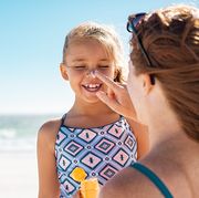 mother applying suntan lotion on daughter face