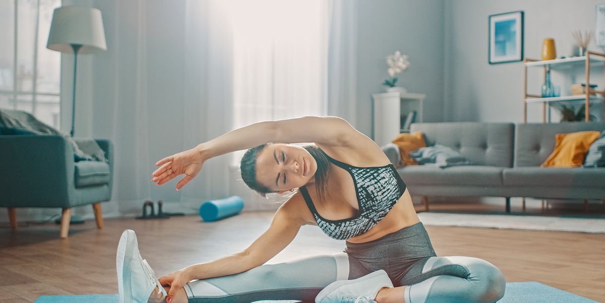 Happy active woman in sport clothes training on yoga mat at home