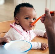 baby being fed with an orange spoon