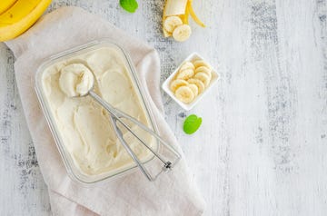 homemade banana ice cream in a glass container with a spoon for ice cream on a wooden background healthy dessert horizontal, top view, copy space